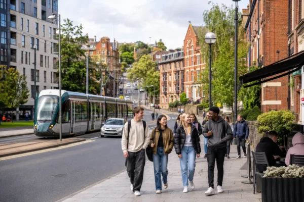 Students walking through Nottingham near tram links, red-brick buildings, cafes, and student housing areas like Lenton, Beeston, City Centre, Radford, and Wollaton.