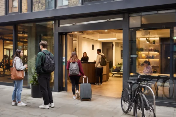 Students arriving at a modern private student halls building with reception, study space, gym access, and city-centre accommodation facilities.