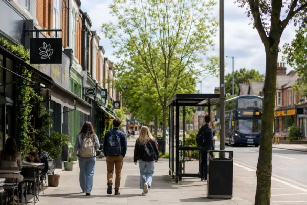 Students walking through Withington near cafes, shops, and a bus stop, showing a calm and practical student area in Manchester.